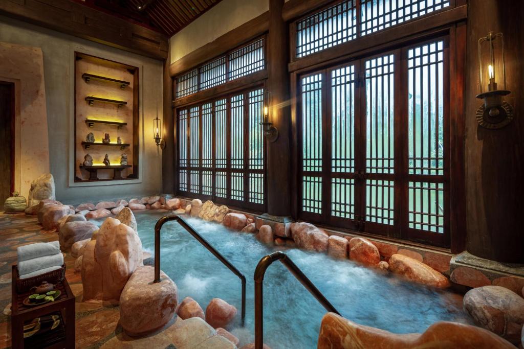 Bể nước ấm được bao quanh bằng đá, gỗ và ánh sáng dịu.