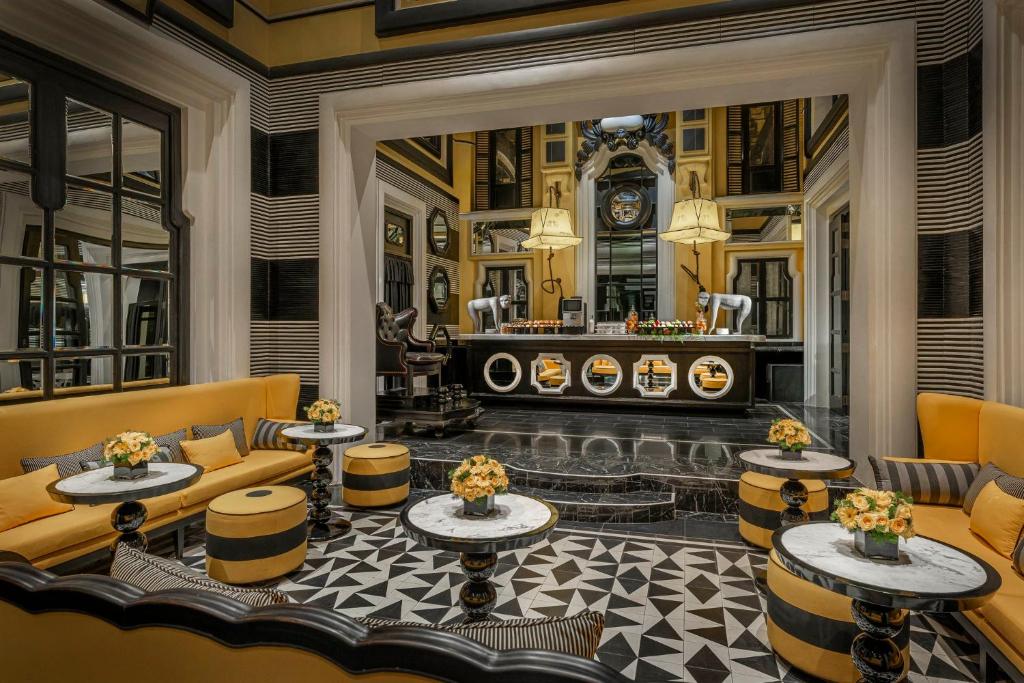 Sofa vàng, bàn trống và các lớp khung đen tạo một lounge vừa cổ điển vừa mang tính sân khấu.