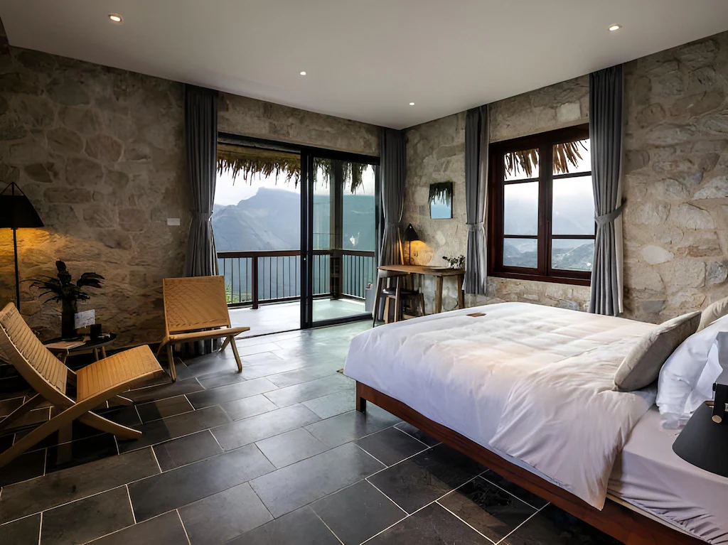 Góc nhìn kép, ghế lounge gỗ và bảng màu xám nâu khiến căn phòng vừa mở rộng vừa có cảm giác trú ẩn.