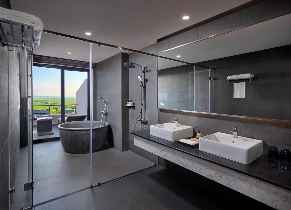 Bồn ngâm, hai lavabo và vùng tắm đứng được tổ chức rõ trong bảng màu đá xám và gỗ.