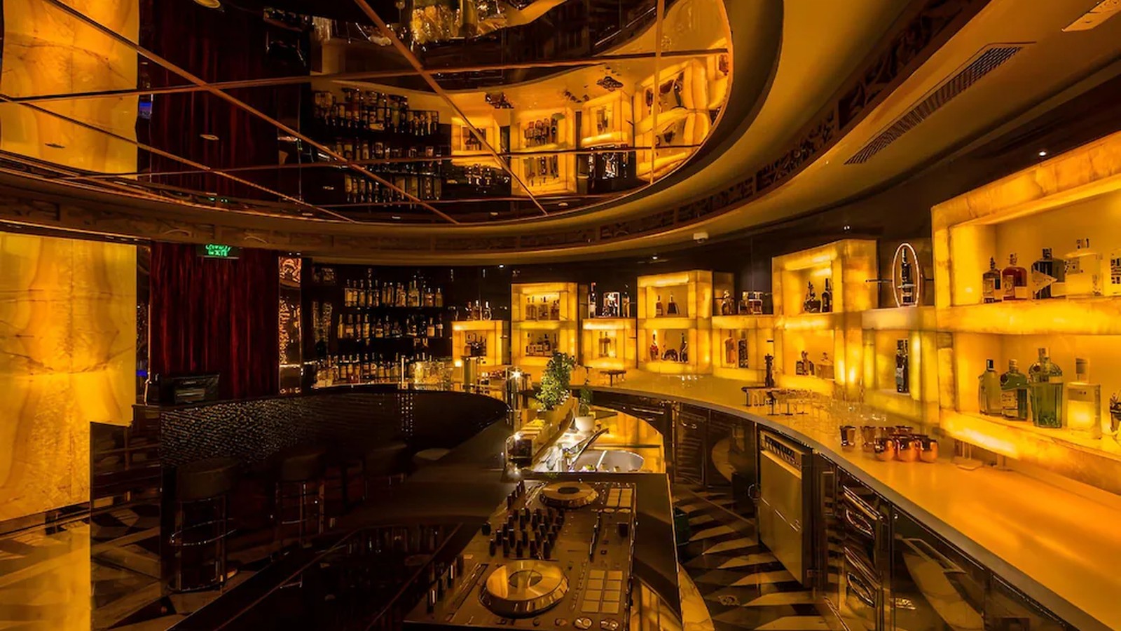 Bar lounge sử dụng ánh sáng hổ phách, quầy cong và trần phản chiếu để tạo chiều sâu.