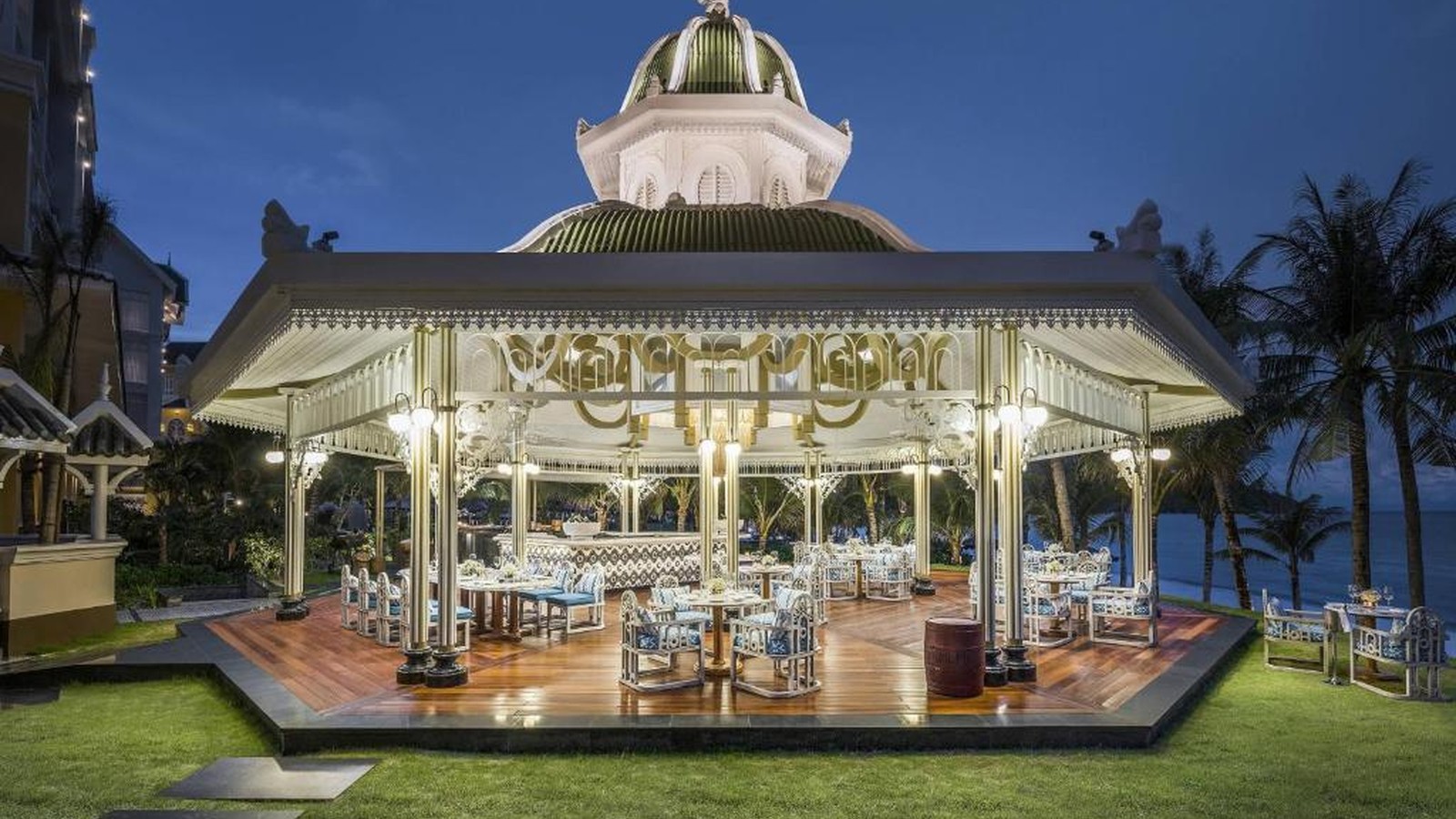 Nhà hàng ngoài trời mang hình ảnh pavilion cổ điển, mở ra vườn và biển.