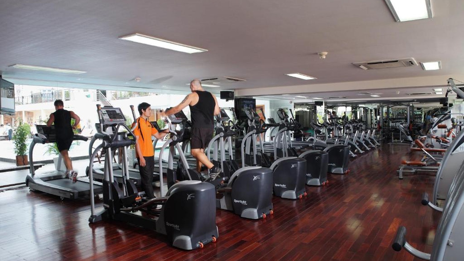 Phòng gym 5 sao có nhiều máy cardio, thiết bị sức mạnh và gương lớn.