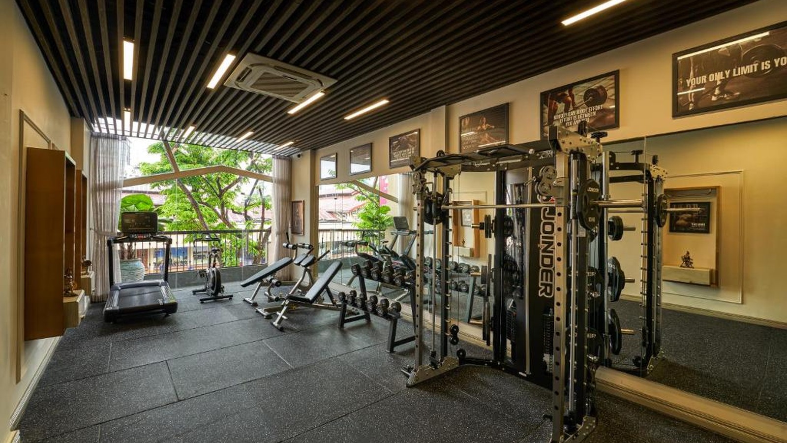 Phòng gym có khu cardio, tạ và máy đa năng trong không gian đón ánh sáng tự nhiên.