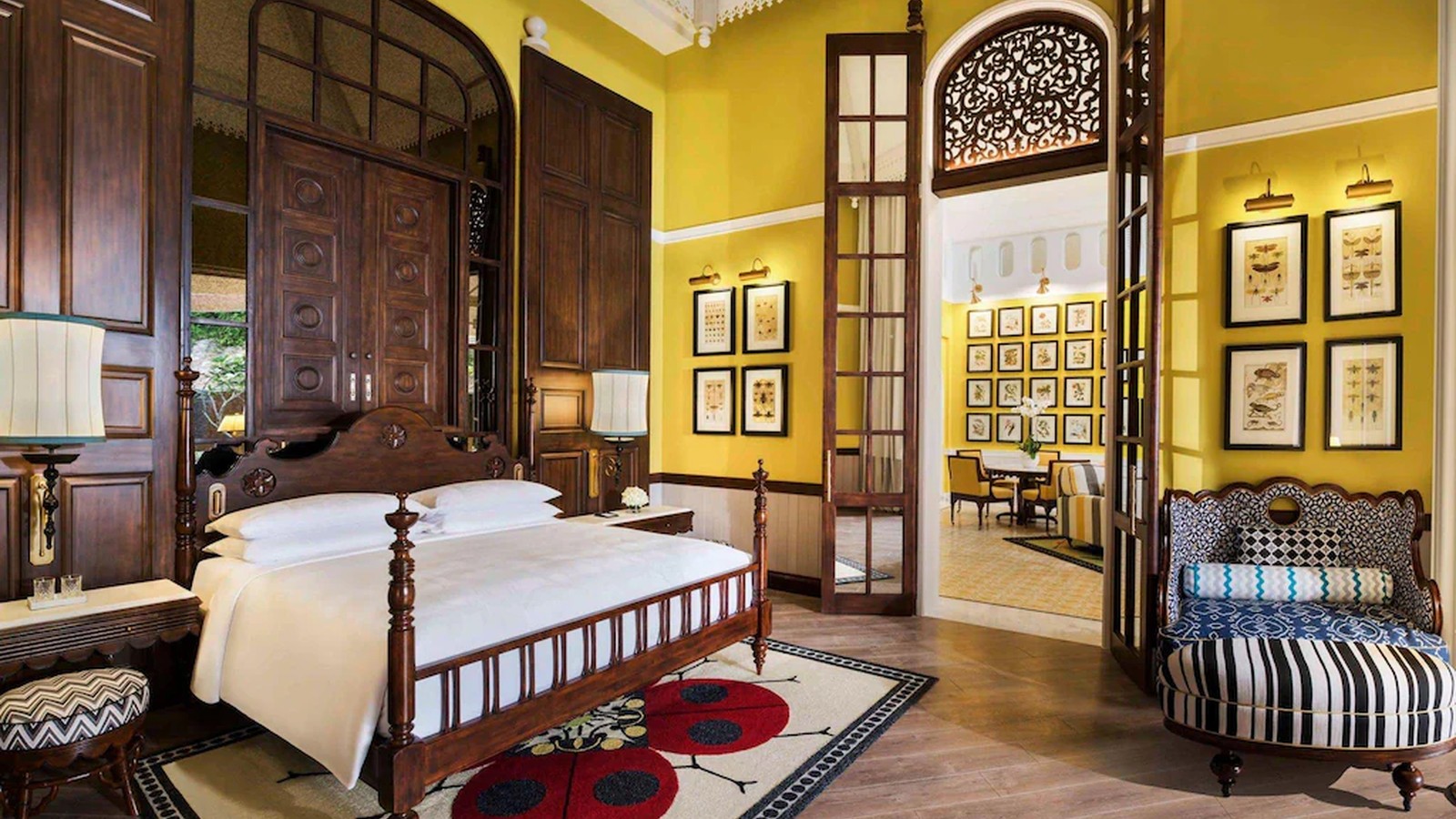 Phòng sắc vàng phối cửa gỗ lớn, thảm hoa và ghế kẻ để tạo nét cổ điển nhiệt đới.