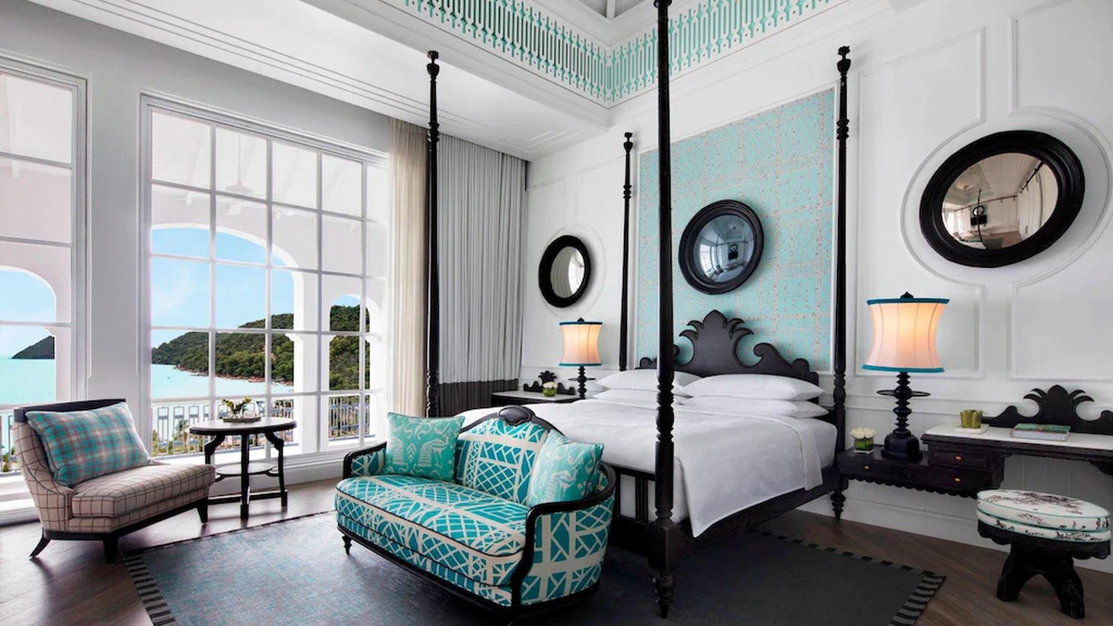 Suite giường bốn cột sử dụng xanh ngọc, gỗ đen và cửa kính lớn để tạo nét lãng mạn hướng biển.