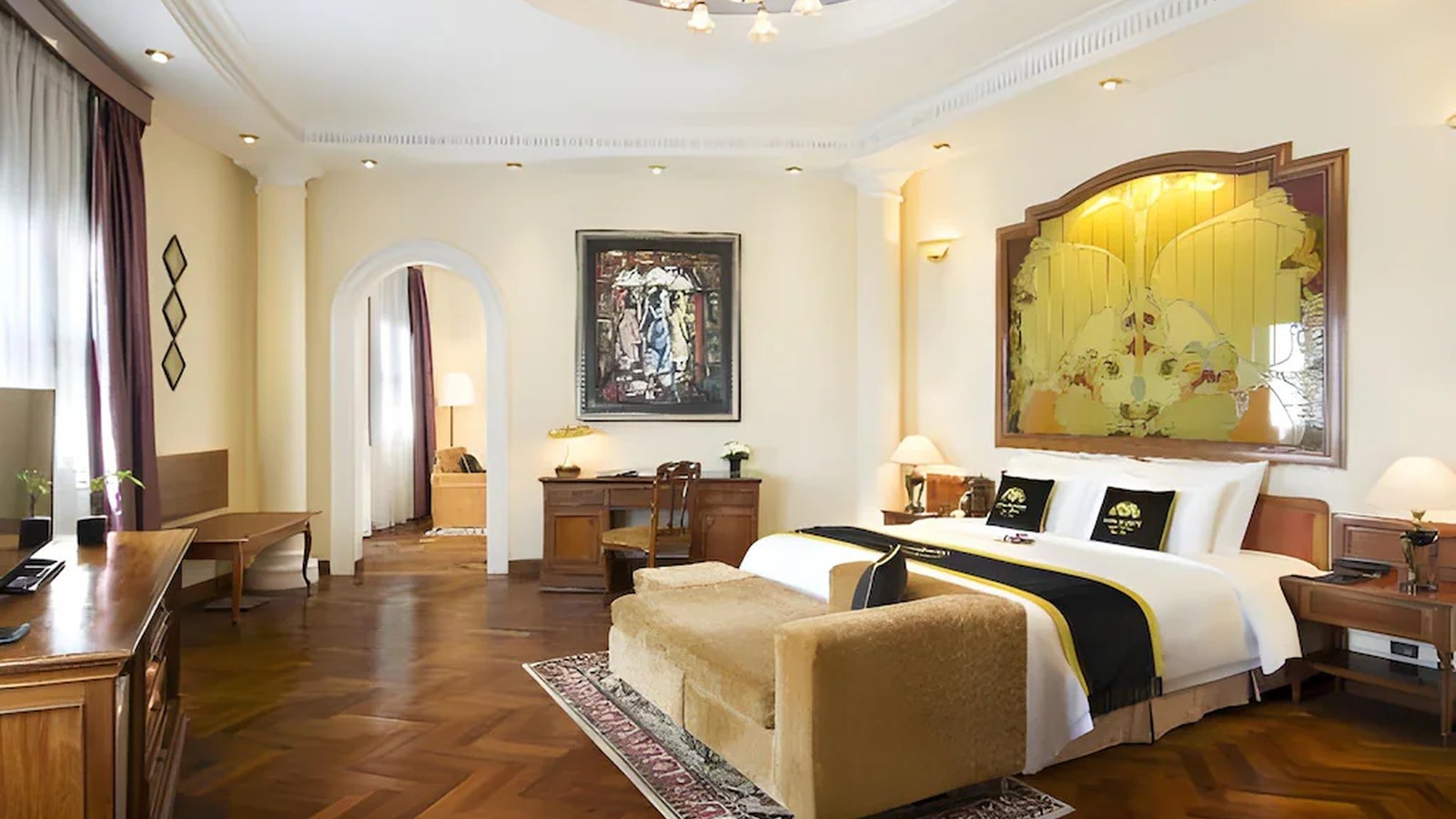 Phòng suite Indochine sử dụng sàn gỗ xương cá, nội thất gỗ và nghệ thuật làm trung tâm thị giác.