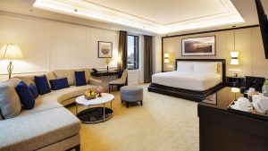 Phòng suite kết hợp khu ngủ, sofa và bàn làm việc trong bố cục rộng rãi.