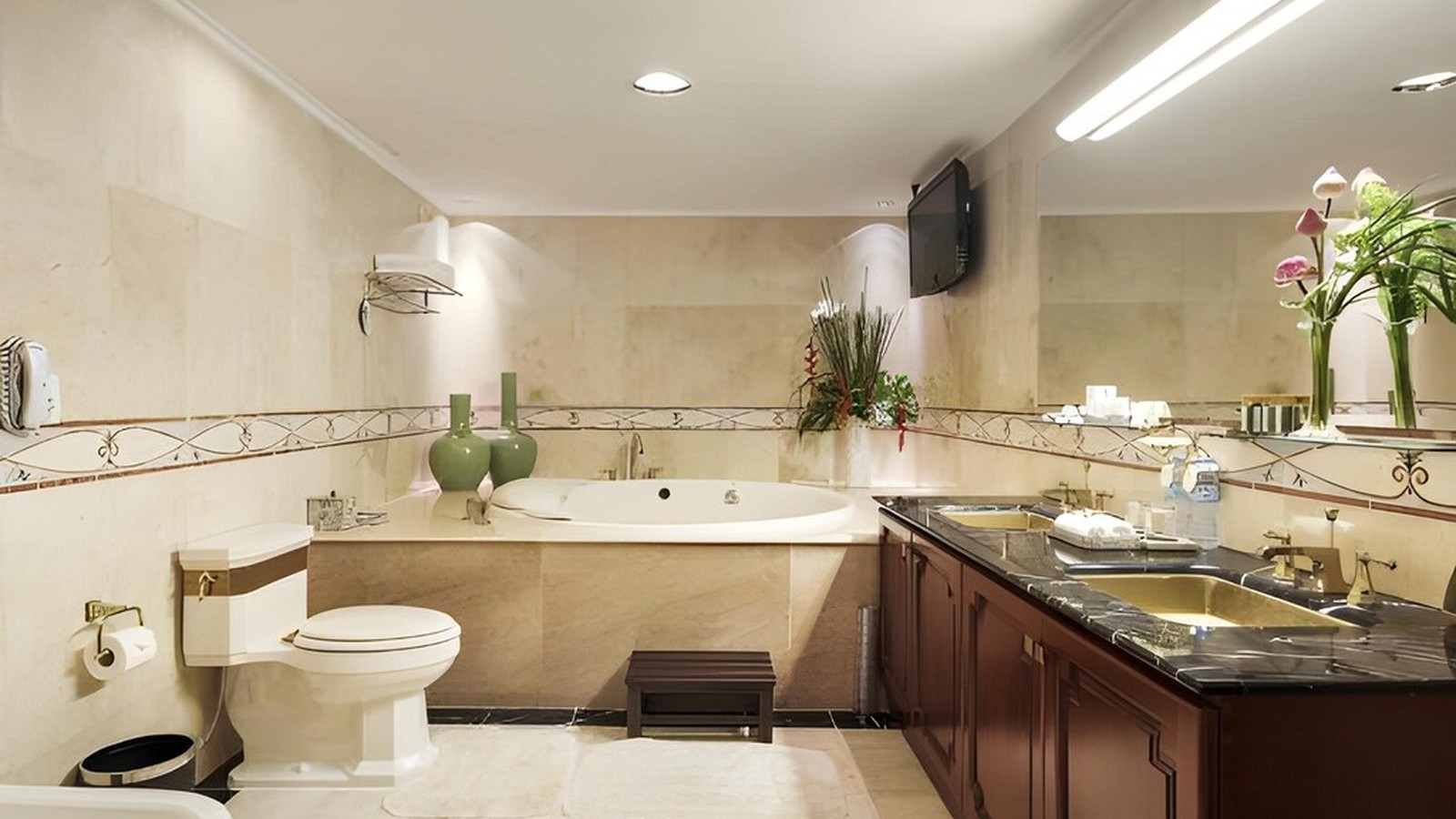Phòng tắm bồn ngâm kết hợp đá sáng, tủ gỗ và họa tiết sàn để giữ nét Đông Dương.