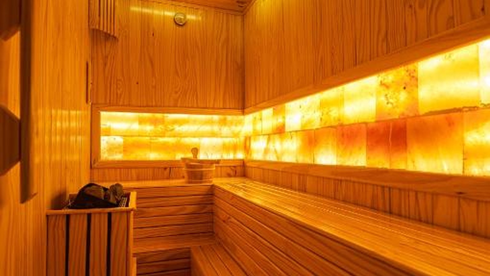 Sauna ốp gỗ và ánh sáng vàng tạo cảm giác ấm, riêng tư và thư giãn.