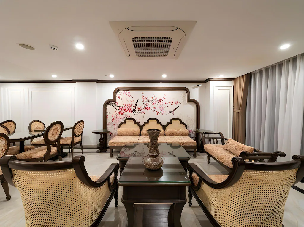 Không gian sinh hoạt khách sạn 4 sao với ghế mây, sofa gỗ và tranh hoa điểu