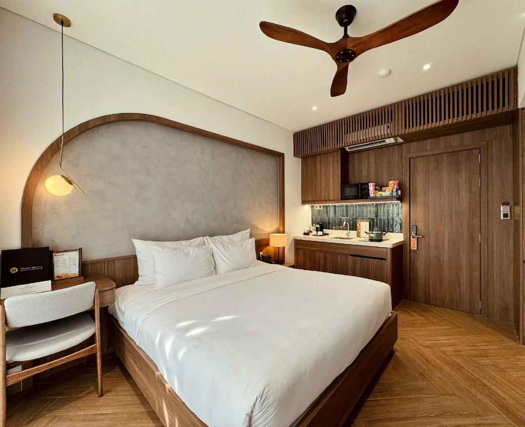 Phòng đôi khách sạn 3 sao hiện đại với giường lớn, bếp nhỏ và nội thất gỗ nâu
