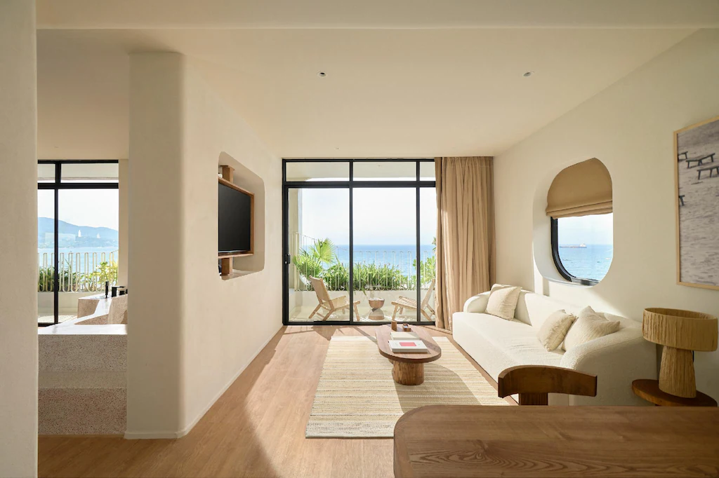 Phòng suite khách sạn 4 sao phong cách Wabi Sabi với phòng khách, gỗ sáng và ban công hướng biển