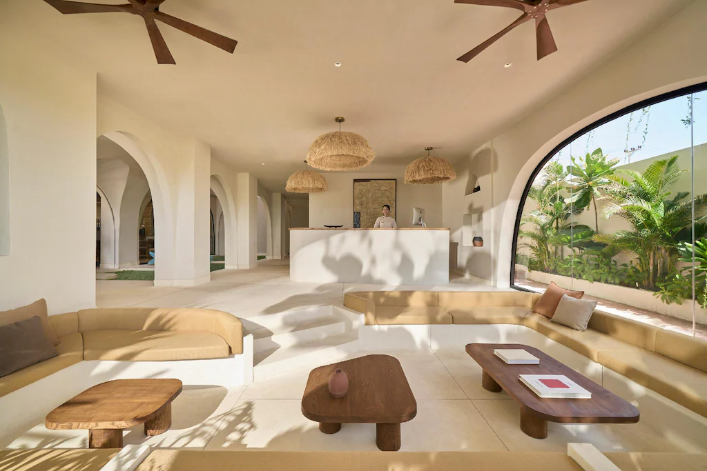 Khu chờ sảnh khách sạn 4 sao Wabi Sabi với sofa âm sàn, bàn gỗ và cửa kính vòm