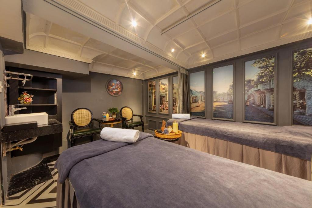 Phòng trị liệu spa khách sạn 4 sao với giường massage, ghế mây và tranh phố cổ