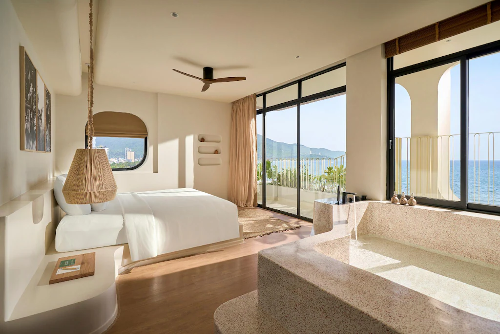 Phòng ngủ khách sạn 4 sao phong cách Wabi Sabi với bồn tắm đá hạt và ban công hướng biển